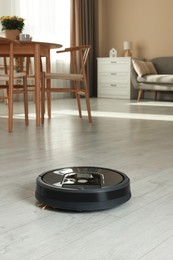 Photo of One robotic vacuum cleaner on wooden floor in living room