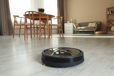 Photo of One robotic vacuum cleaner on wooden floor in living room