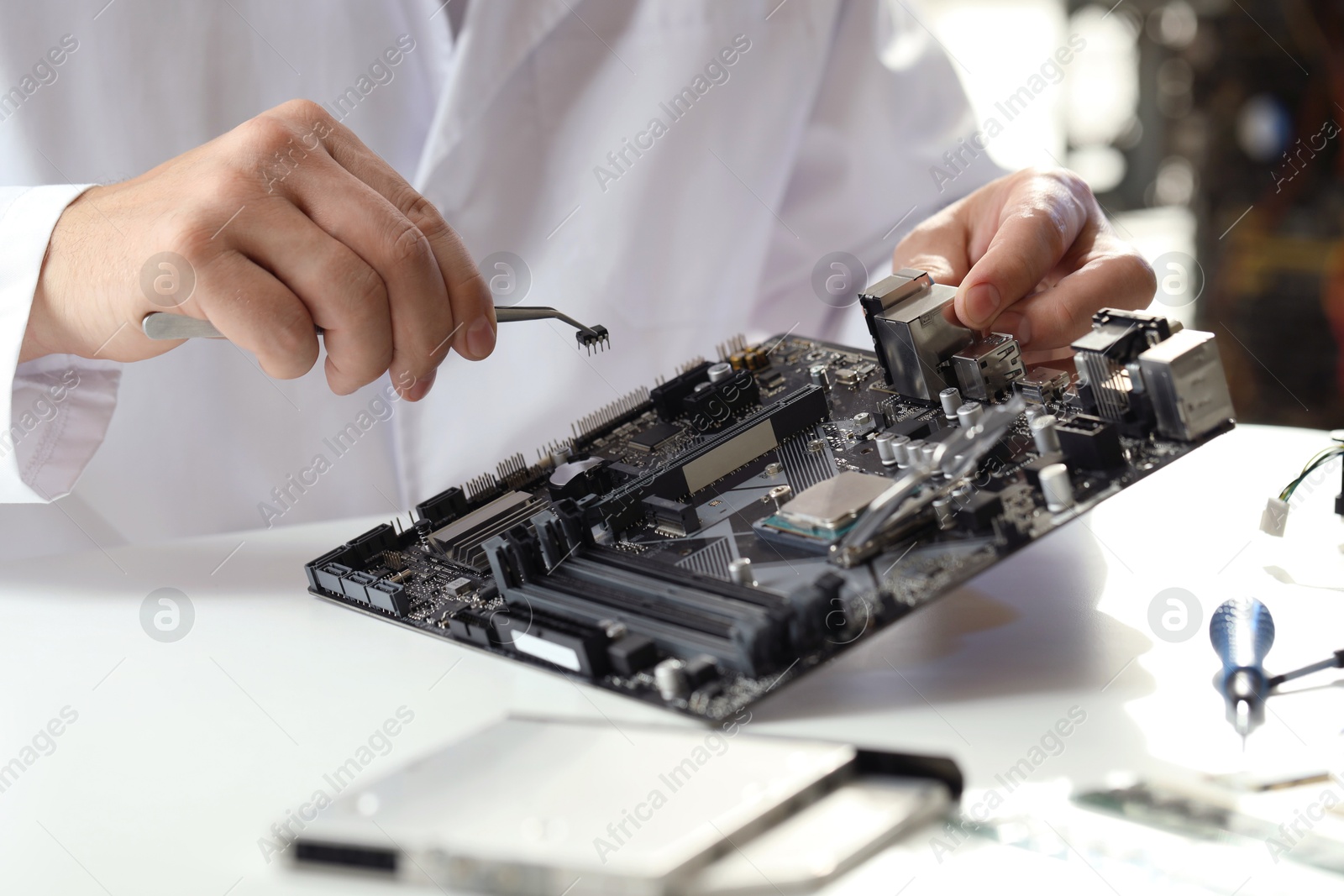 Photo of Man installing computer chip onto motherboard at white table, closeup