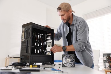 Photo of Man installing fan into computer at white table