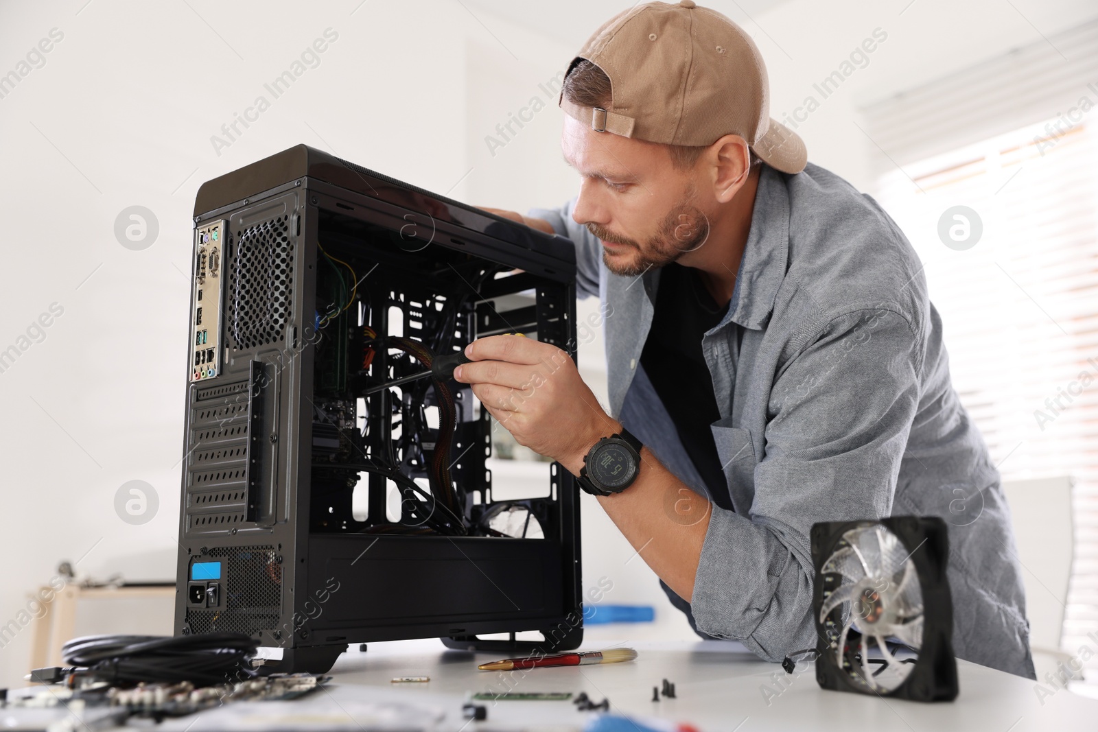 Photo of Man installing fan into computer at white table