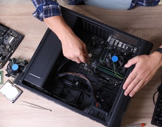 Photo of Man assembling new computer at wooden table, top view