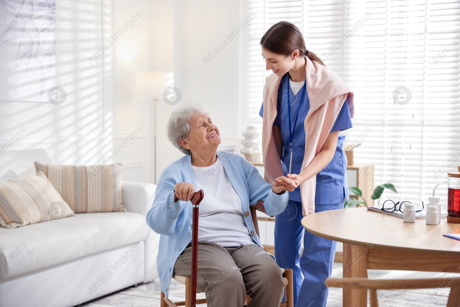 Photo of Caregiver supporting senior woman indoors. Home health care service