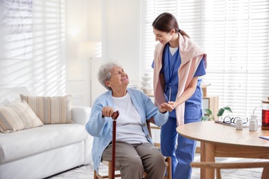 Photo of Caregiver supporting senior woman indoors. Home health care service