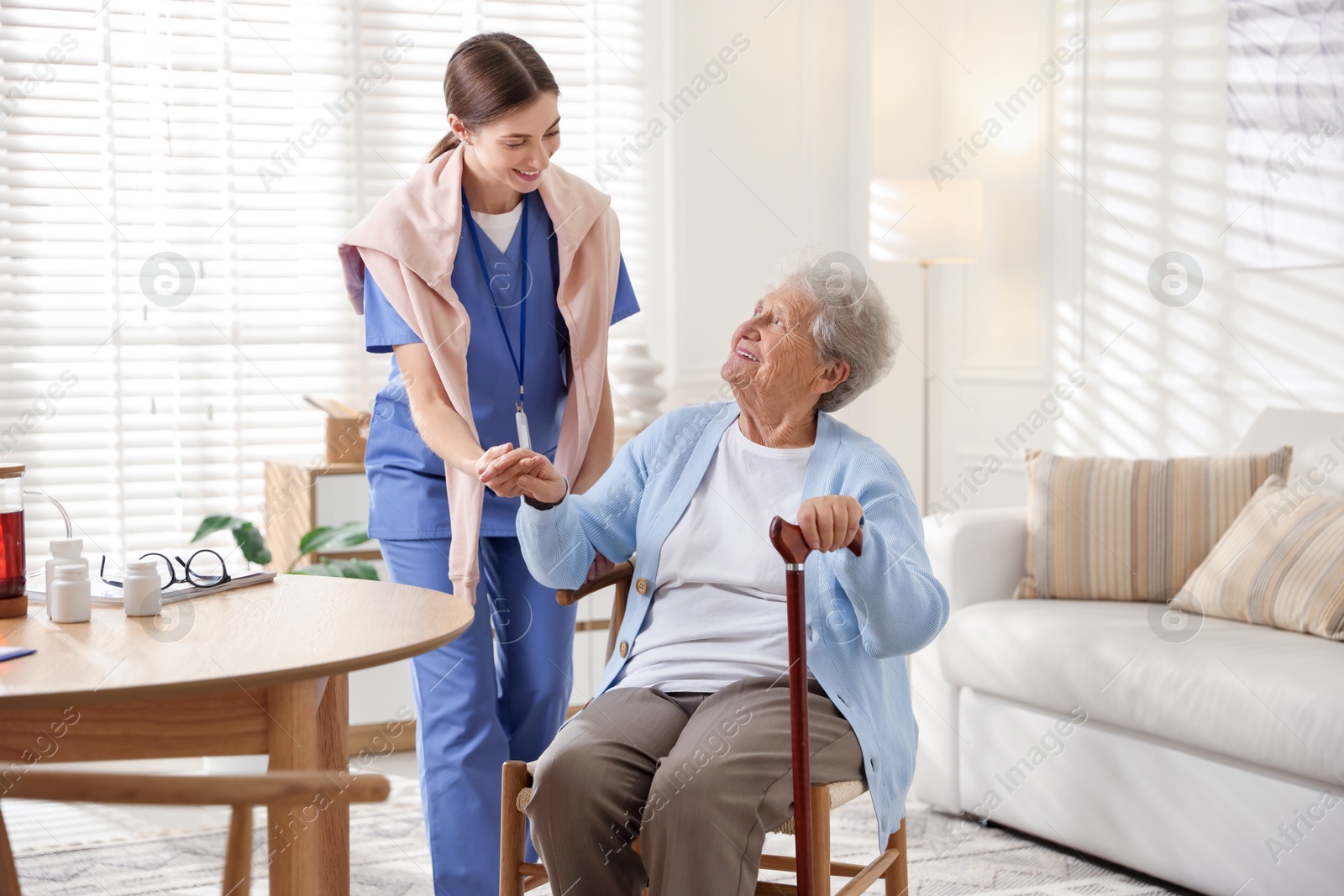 Photo of Caregiver supporting senior woman indoors. Home health care service