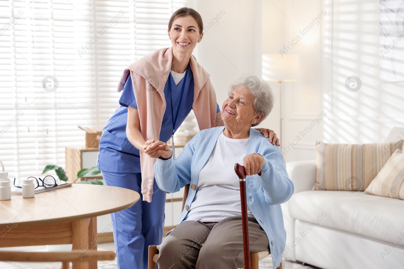 Photo of Caregiver supporting senior woman indoors. Home health care service