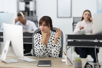 Photo of Saleswoman talking to client via headset at desk in office