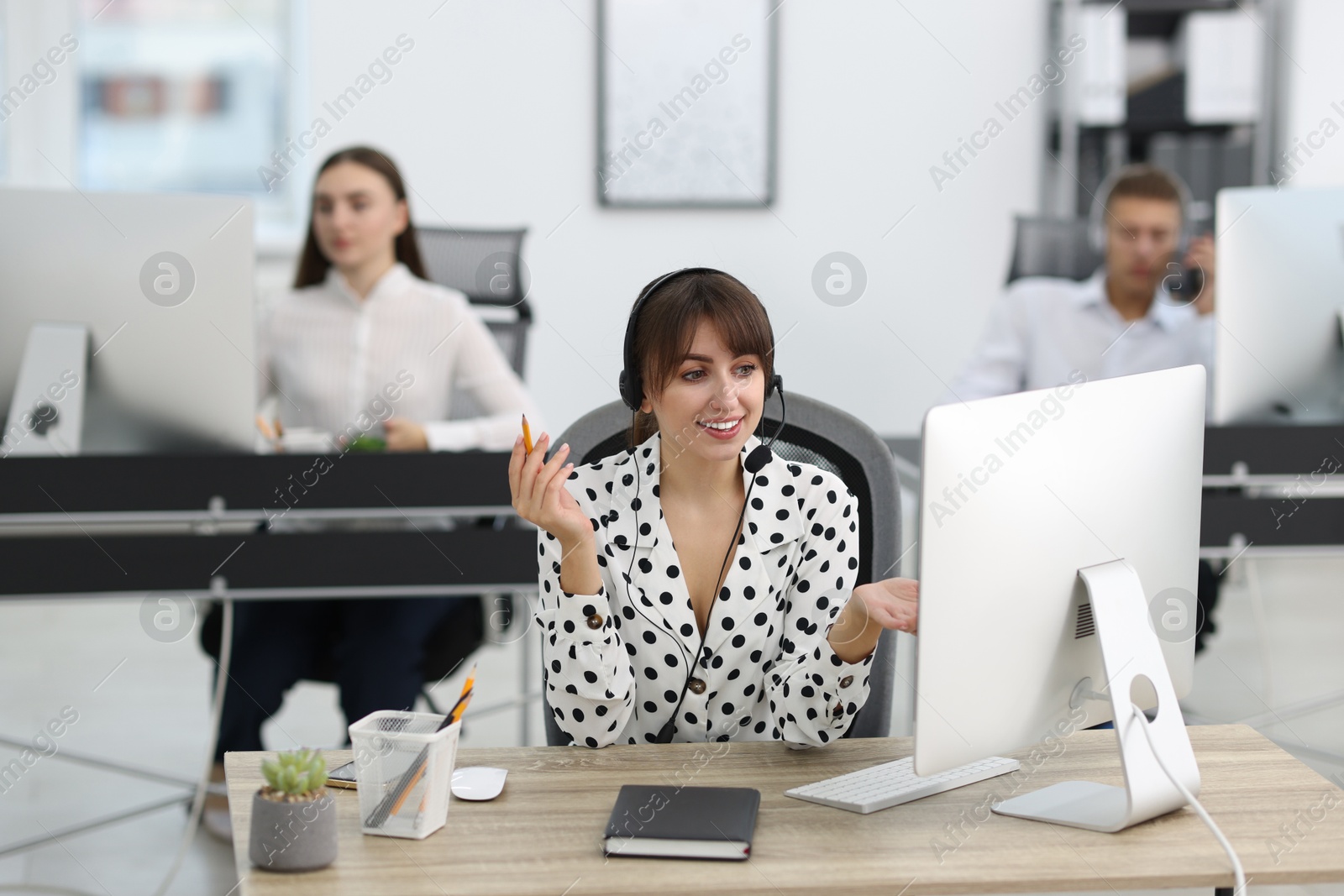 Photo of Saleswoman talking to client via headset at desk in office