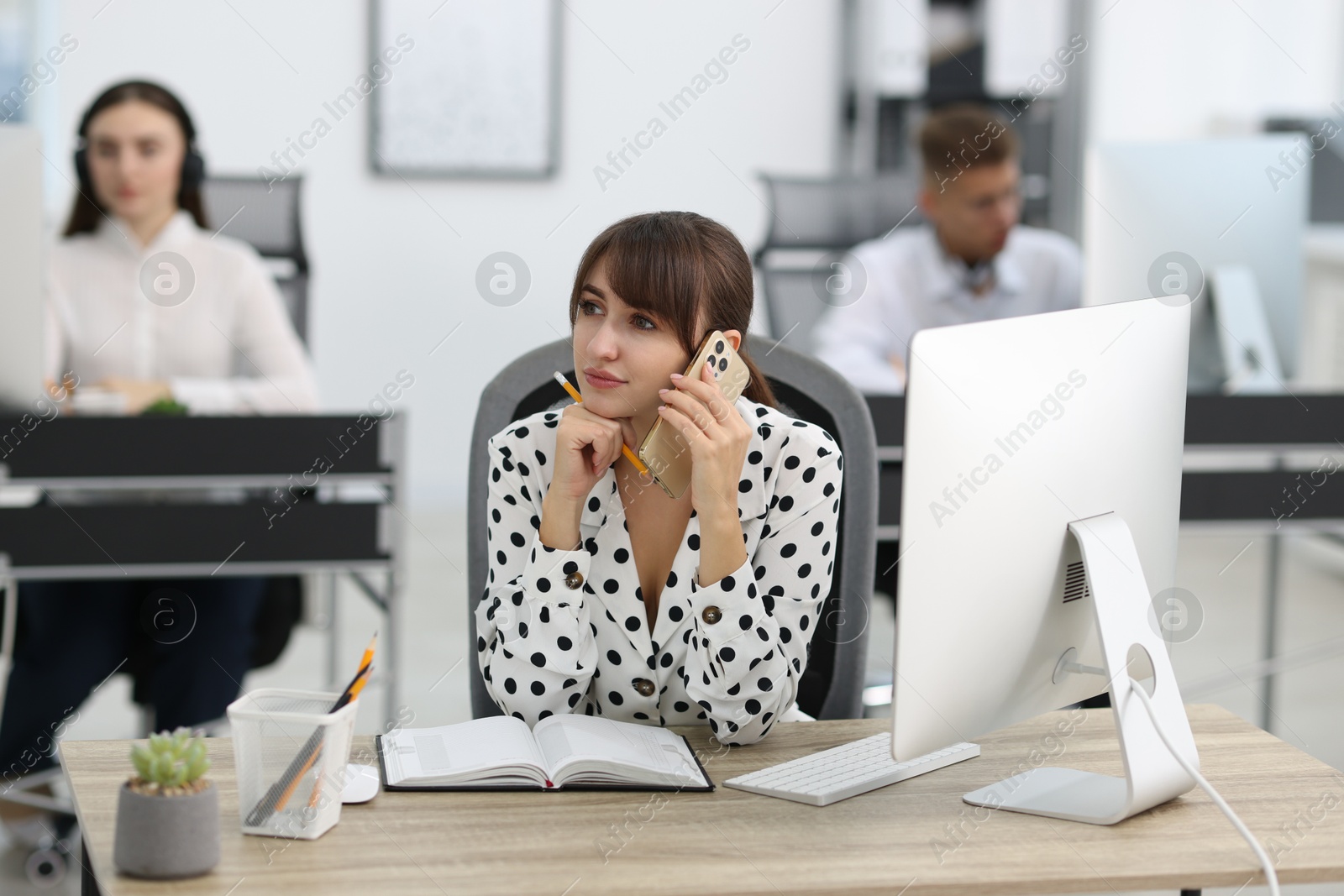 Photo of Saleswoman talking on phone at desk in office