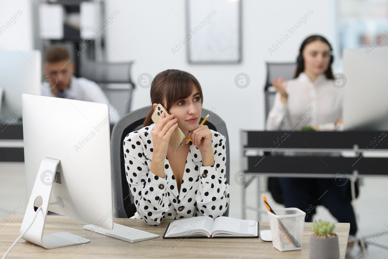 Photo of Saleswoman talking on phone at desk in office