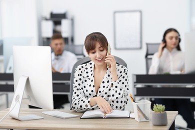 Photo of Saleswoman talking on phone at desk in office