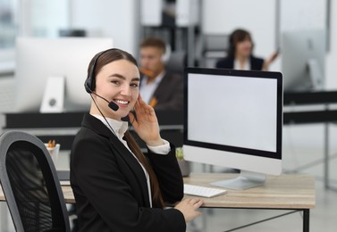 Photo of Saleswoman talking to client via headset at desk in office