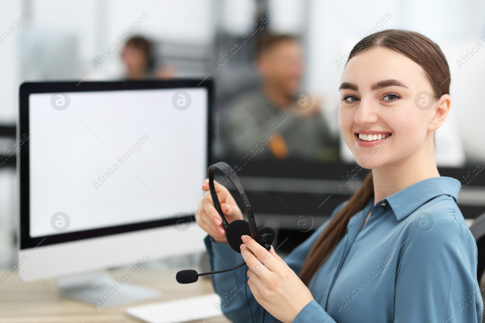 Photo of Saleswoman with headset at desk in office