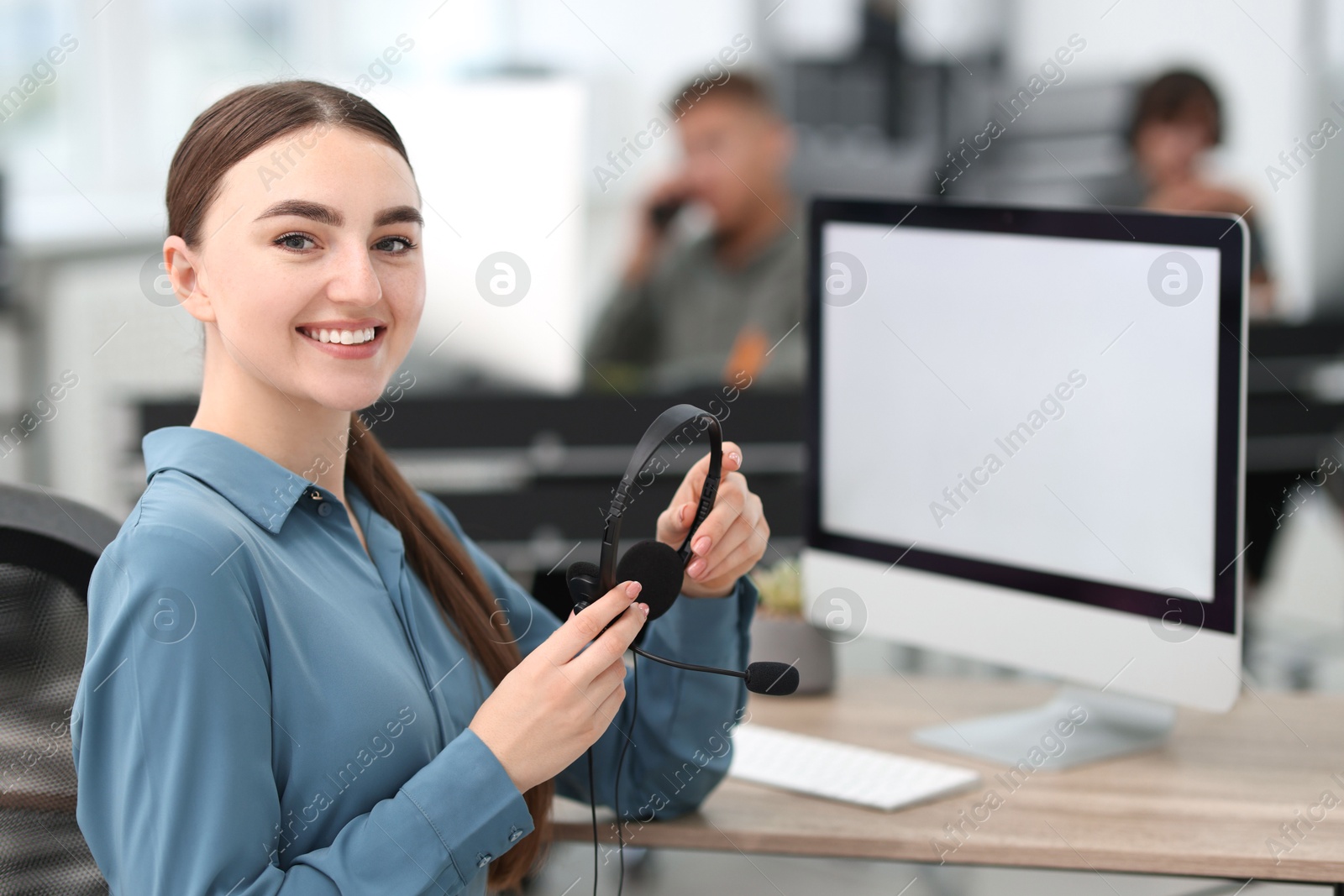 Photo of Saleswoman with headset at desk in office