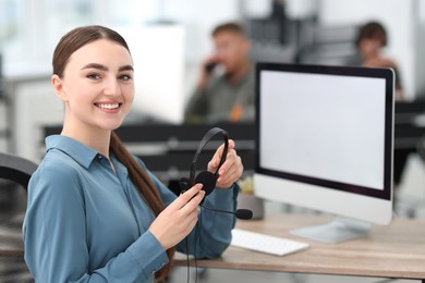 Photo of Saleswoman with headset at desk in office