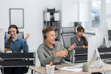 Photo of Sales department. People with headsets working in office, selective focus