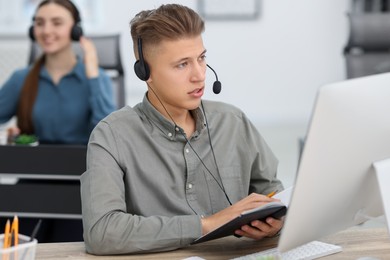 Photo of Salesman talking to client via headset at desk in office