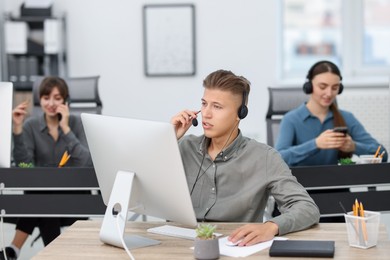 Photo of Salesman talking to client via headset at desk in office