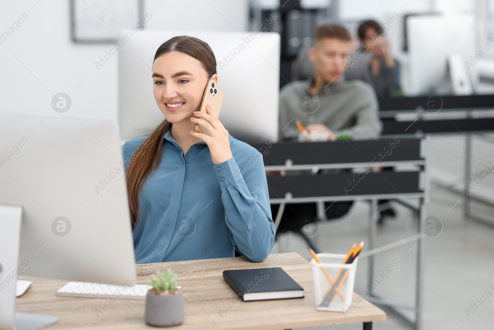 Photo of Saleswoman talking on phone at desk in office