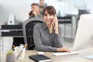 Photo of Saleswoman talking on phone at desk in office