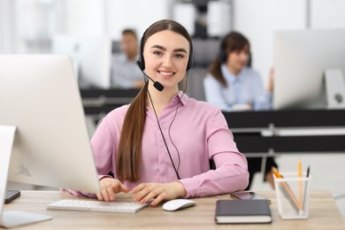 Photo of Saleswoman talking to client via headset at desk in office