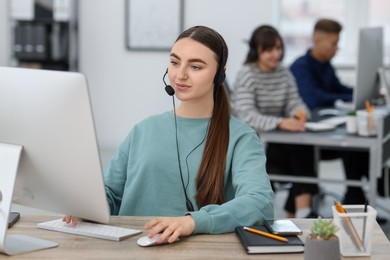 Photo of Saleswoman talking to client via headset at desk in office