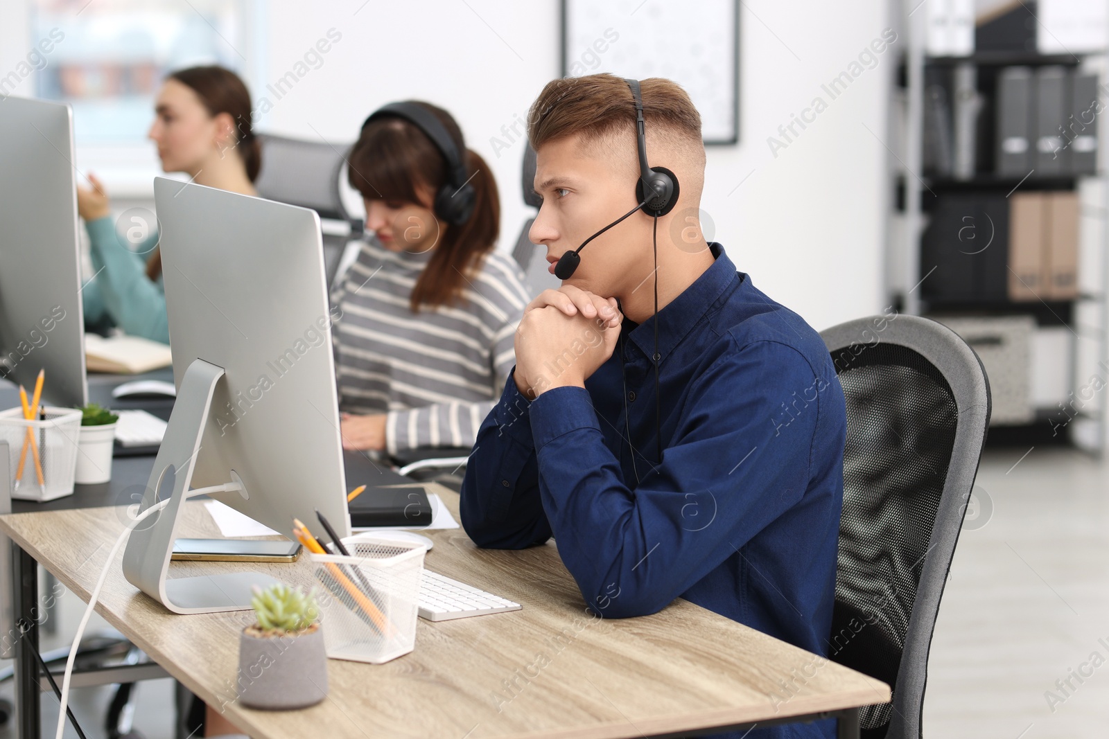 Photo of Salesman talking to client via headset at desk in office