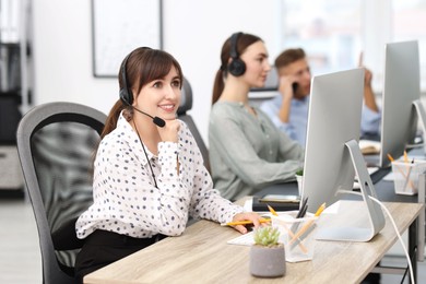 Photo of Saleswoman talking to client via headset at desk in office