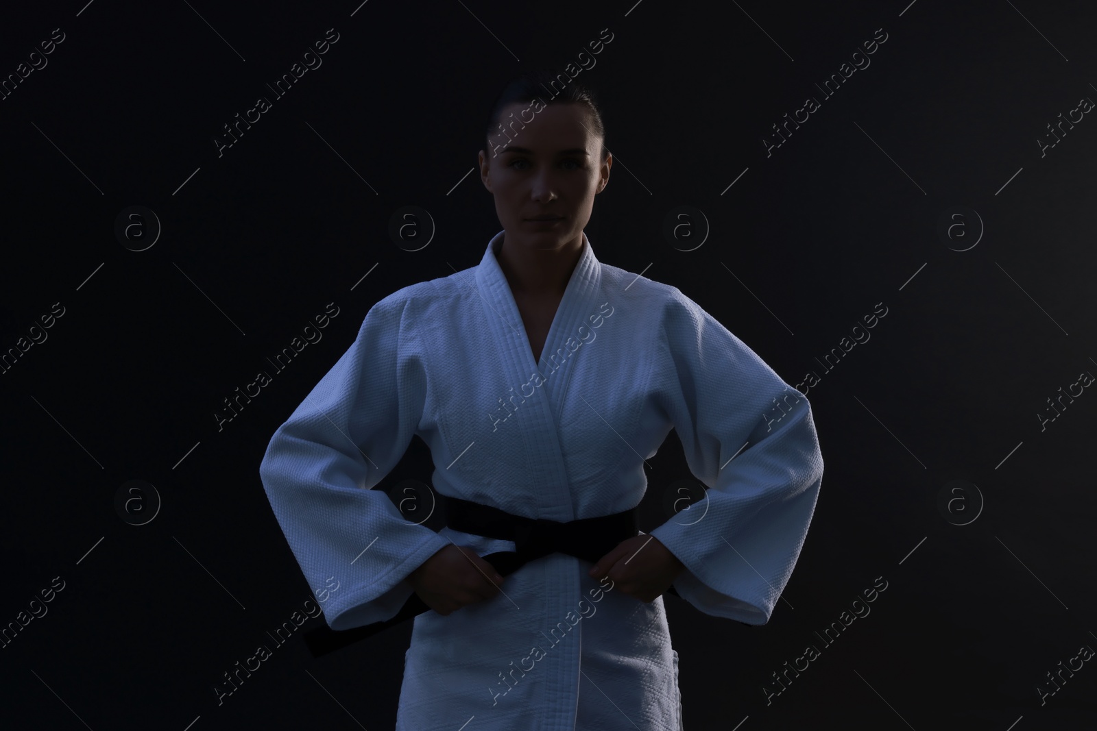 Photo of Silhouette of karate fighter in kimono on dark background