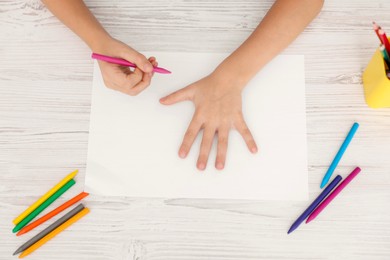 Photo of Boy contouring his palm at light wooden table, top view