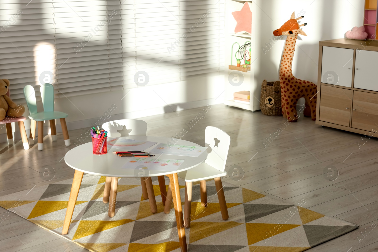 Photo of Wooden furniture, drawings and toys in light child's room