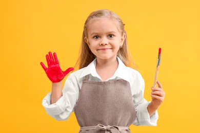 Photo of Cute girl drawing with palm on orange background