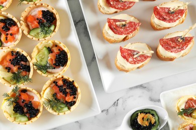 Photo of Many different tasty canapes on white marble table, flat lay