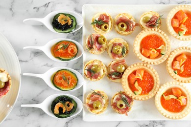 Photo of Many different tasty canapes on white marble table, flat lay