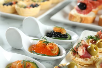 Photo of Many different tasty canapes on white marble table, closeup