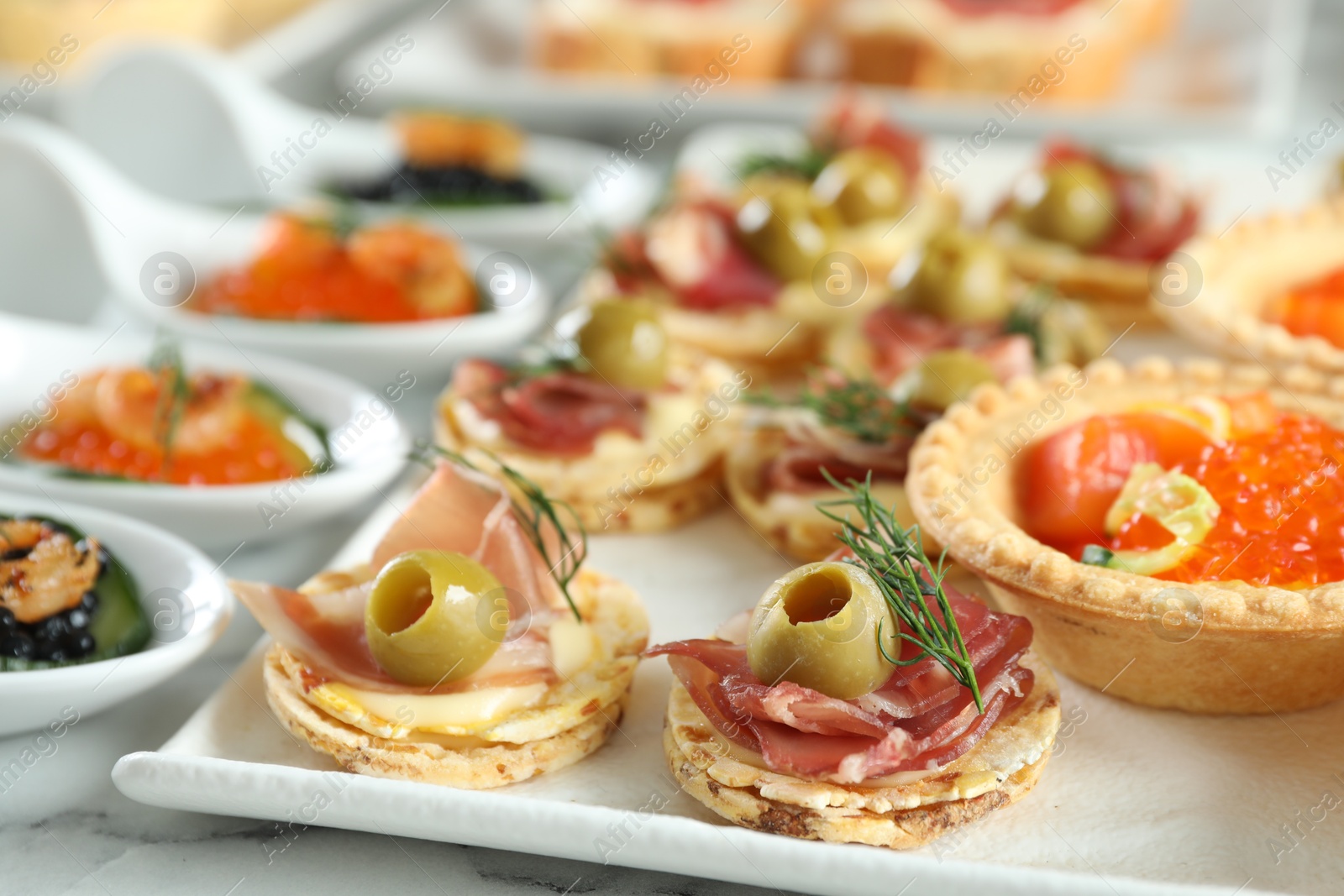 Photo of Many different tasty canapes on white marble table, closeup