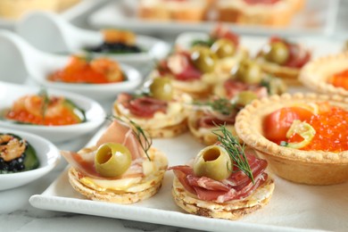 Photo of Many different tasty canapes on white marble table, closeup