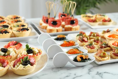 Photo of Many different tasty canapes on white marble table, closeup