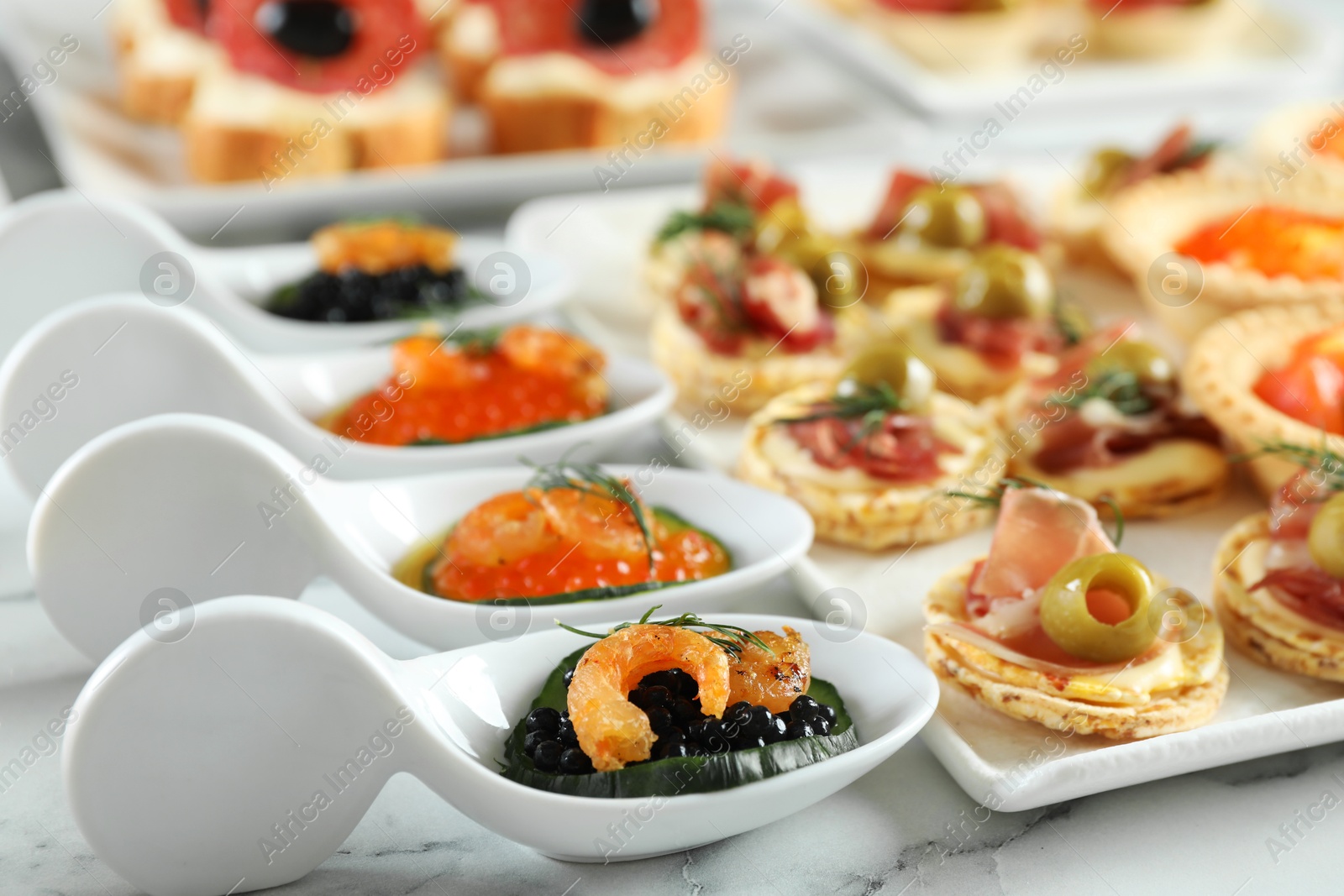 Photo of Many different tasty canapes on white marble table, closeup