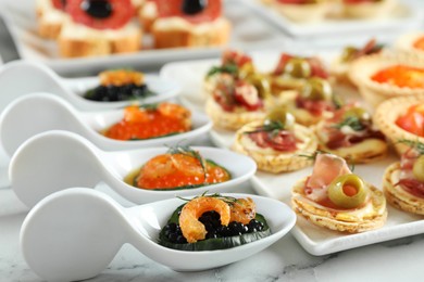 Photo of Many different tasty canapes on white marble table, closeup