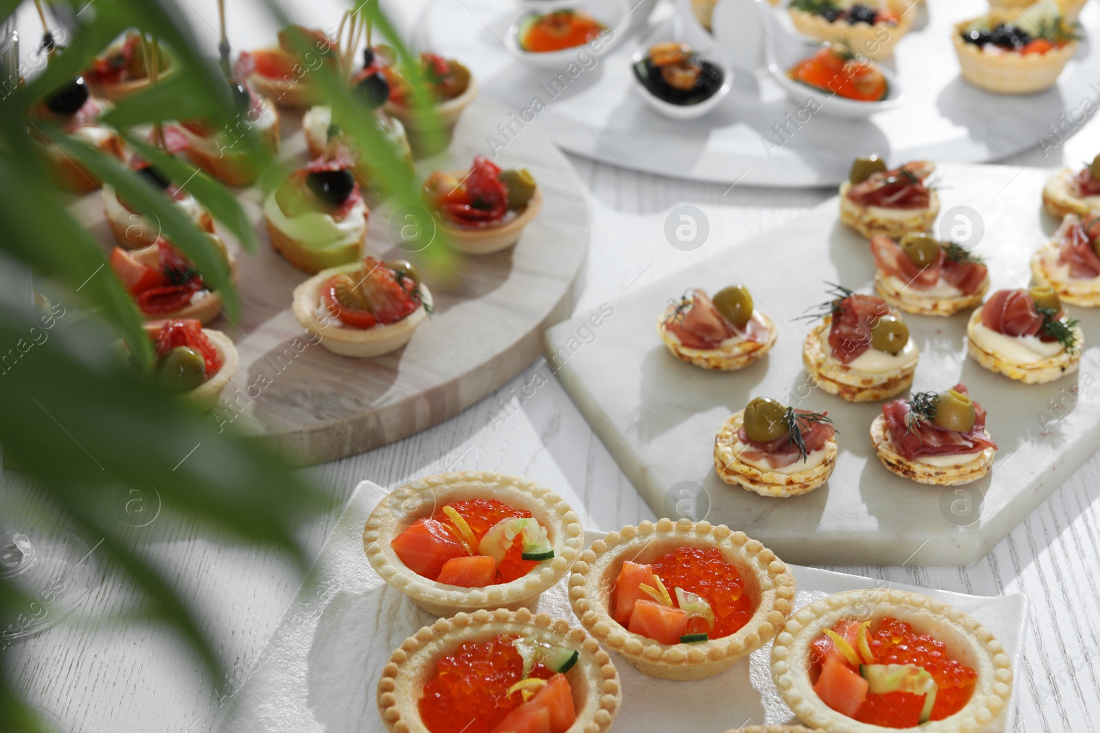 Photo of Many different tasty canapes on white wooden table, closeup