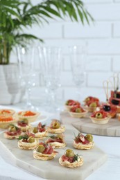 Photo of Many different tasty canapes on white wooden table, closeup