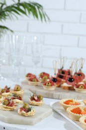 Photo of Many different tasty canapes on white wooden table, closeup