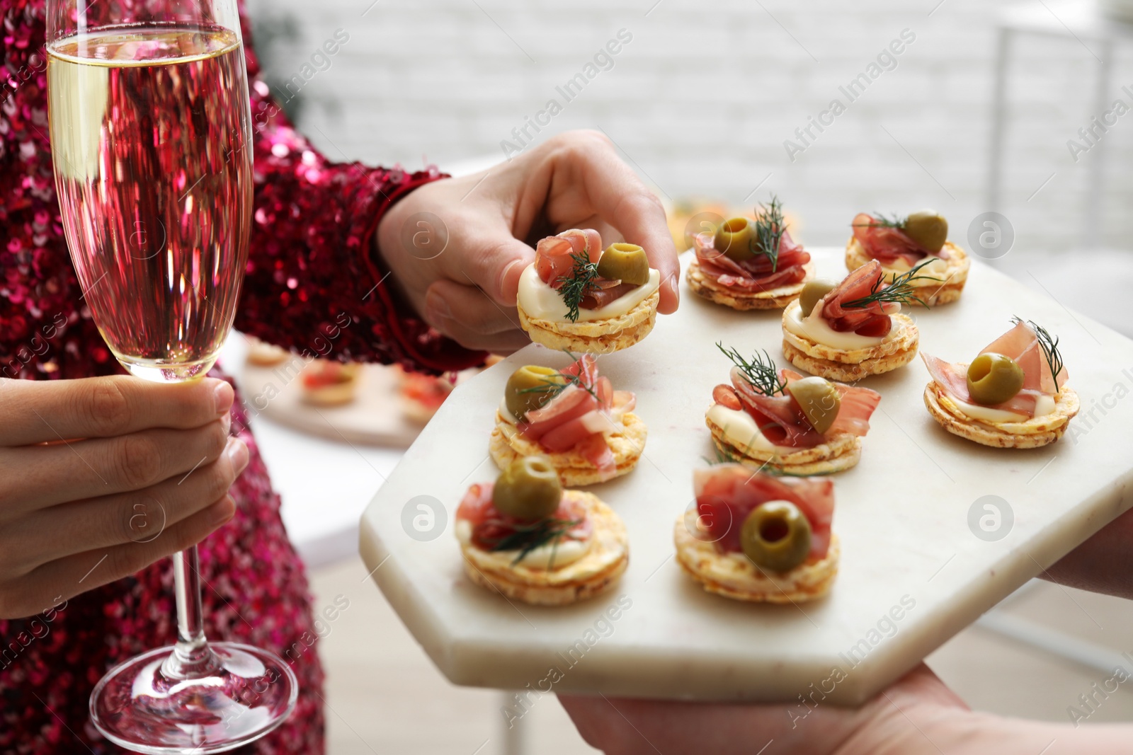 Photo of Woman taking tasty canape from waiter with board indoors, closeup