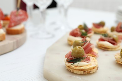 Photo of Many different tasty canapes on white wooden table, closeup