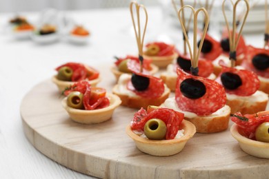 Photo of Many different tasty canapes on white wooden table, closeup