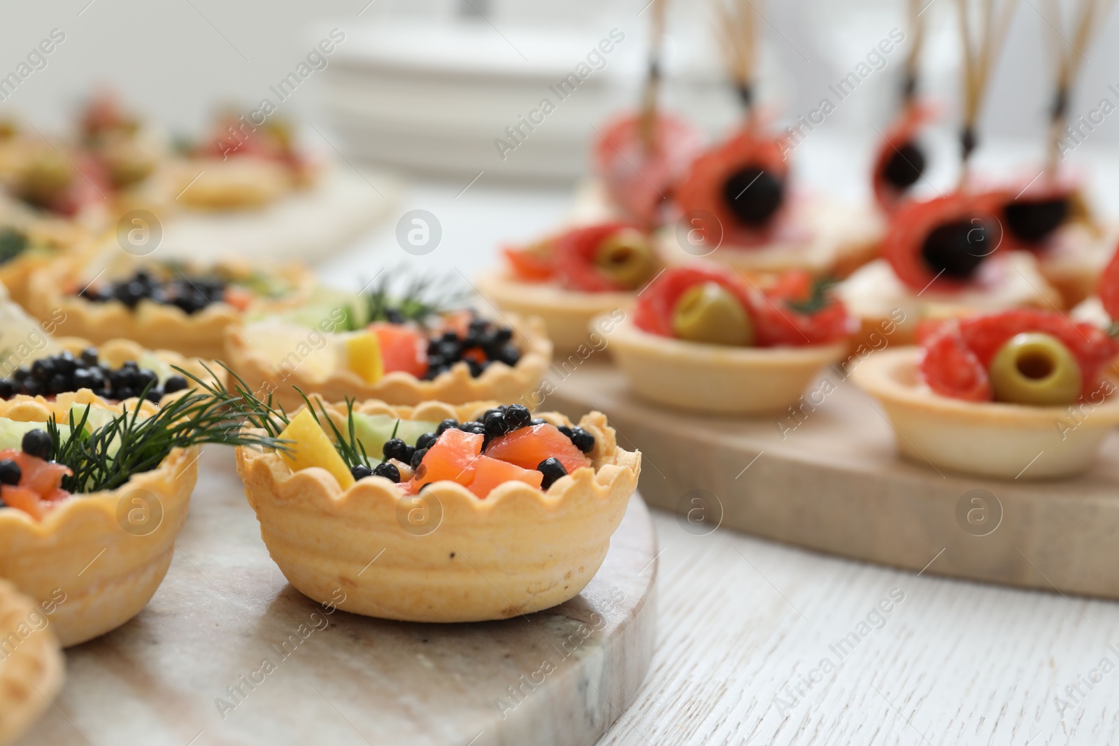 Photo of Many different tasty canapes on white wooden table, closeup