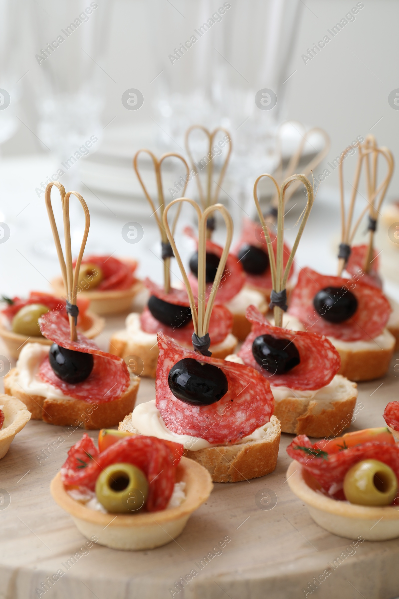 Photo of Many different tasty canapes on wooden board, closeup