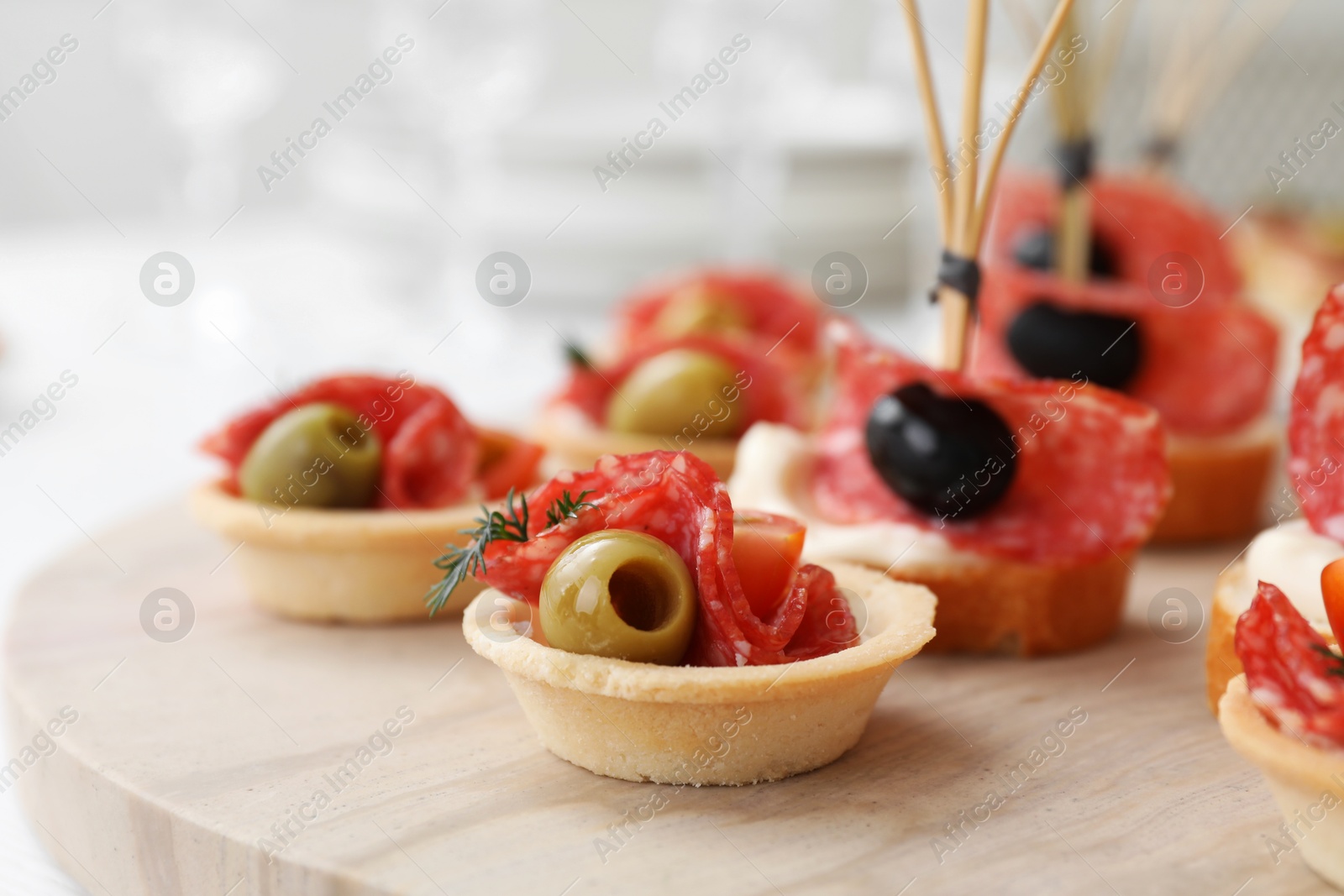 Photo of Many different tasty canapes on wooden board, closeup