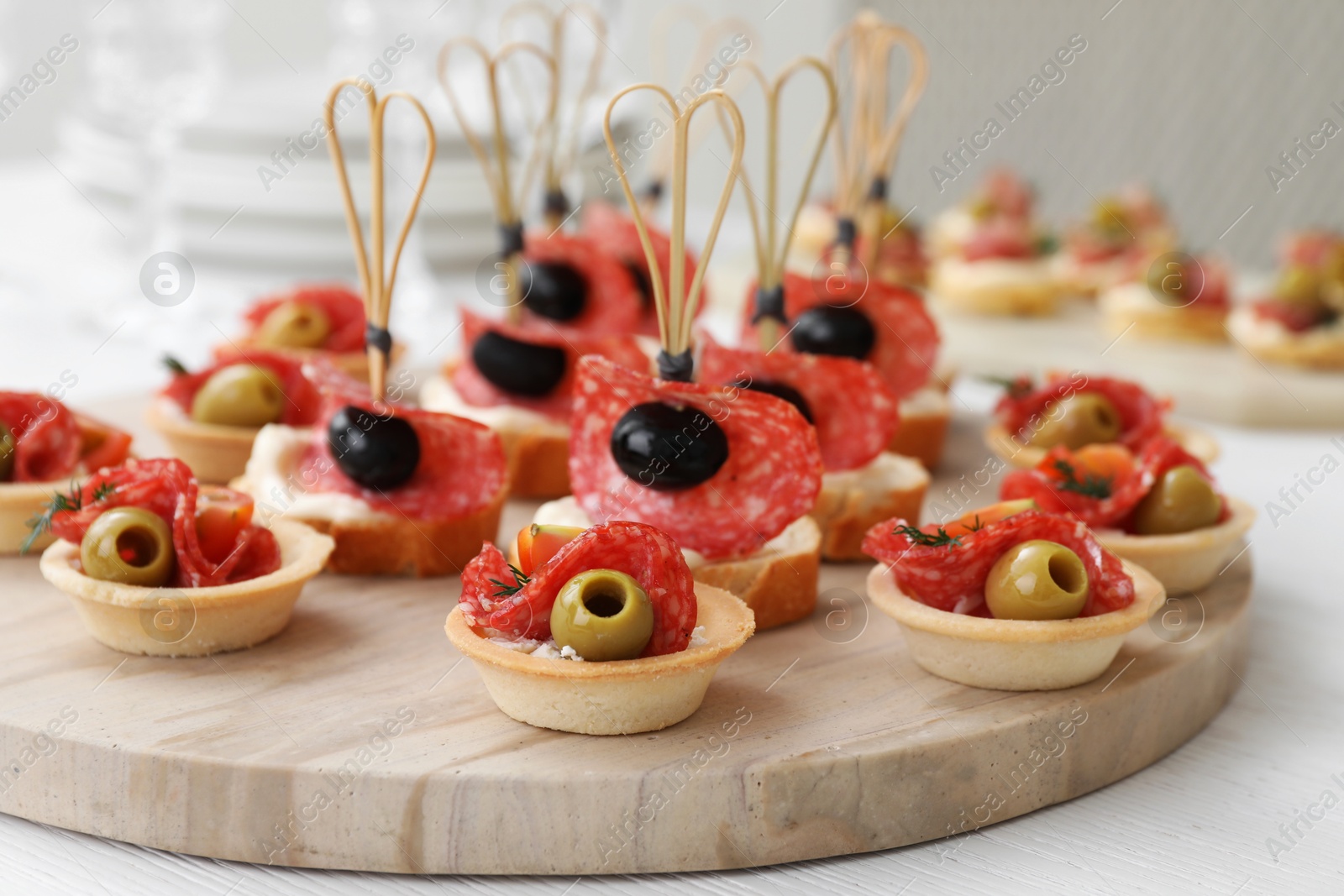 Photo of Many different tasty canapes on white wooden table, closeup